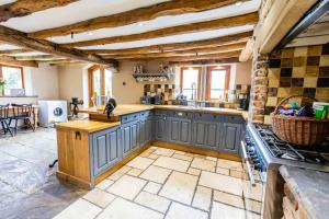 a large kitchen with blue cabinets and a stone floor at Bence Farm Yorkshire, barn conversion with hot tub karaoke great views between leeds and sheffield 