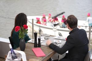 Ein Mann und eine Frau sitzen an einem Tisch auf einem Boot in der Unterkunft Hotel Restaurant Brasserie Feestzaal Ahoi, Kortrijk in Kortrijk
