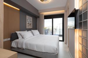 1 dormitorio con cama blanca y ventana grande en LUX&EASY Athens Downtown Residences en Atenas