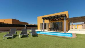 a backyard with a pool and chairs and a house at Villa Calima by Calima Villas in Costa de Antigua