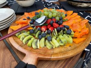 a plate of fruit on a cutting board with a spoon at Muunga Bush Lodge & Spa in Hoedspruit