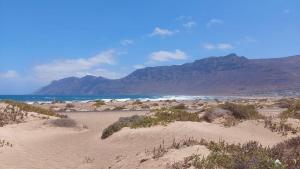 a beach with mountains in the background and the ocean at Dunas de Famara in Famara