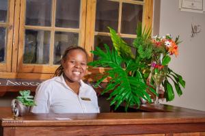 Eine Frau, die an einem Tresen mit Blumen sitzt. in der Unterkunft Avoca Vale Country Hotel in Louis Trichardt