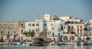 een boot in het water voor gebouwen bij Corte Kyrios Exclusive Suite XVIII Secolo in Trani