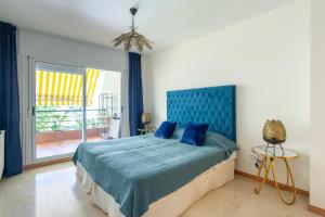 a bedroom with a bed with a blue headboard and a window at Letmalaga Campos de Guadalmina in Marbella