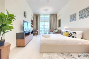 salon z łóżkiem i telewizorem w obiekcie Homely Studio in Azizi Aliyah Residence Al Jadaf by Deluxe Holiday Homes w Dubaju