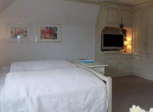 a bedroom with a white bed and a flat screen tv at App-Sturmhaube-1 in Tinnum