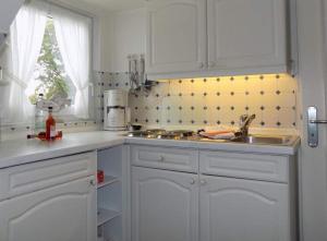 a kitchen with white cabinets and a sink and a window at App-Sturmhaube-1 in Tinnum