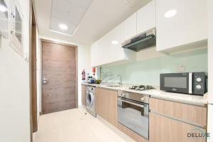 a kitchen with a microwave oven and a stove at Homely Studio in Azizi Aliyah Residence Al Jadaf by Deluxe Holiday Homes in Dubai