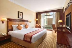 リヤドにあるRamada by Wyndham Hotel Riyadhの大型ベッドとテレビが備わるホテルルームです。