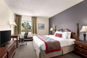 um quarto de hotel com uma cama, uma secretária e uma televisão em Ramada by Wyndham Arcata em Arcata