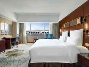 a hotel room with a large white bed and a desk at Pullman Guangzhou Baiyun Airport - Canton Fair Free Shuttle Bus & Official Registration Agency in Guangzhou