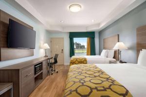 a hotel room with two beds and a flat screen tv at Baymont by Wyndham Kingwood in Kingwood