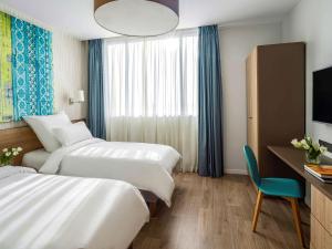 a hotel room with two beds and a desk at Adagio Jeddah City Center in Jeddah