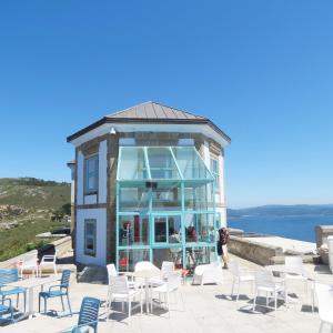 a building with chairs and tables in front of it at Hotel O Semaforo in Finisterre