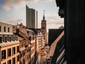 eine Stadtstraße mit Gebäuden und einem Uhrturm in der Unterkunft Luga Homes - Nikolaikirche in Leipzig