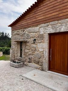 - un bâtiment en pierre avec une porte en bois à l'avant dans l'établissement Recanto de Moulães, à Monção