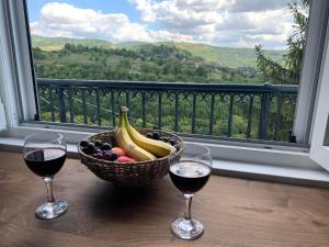 a basket of fruit and two glasses of wine on a balcony at Tsarevets Panorama in Veliko Tŭrnovo
