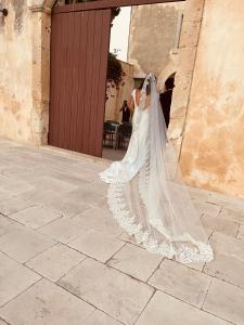 Eine Braut in einem Hochzeitskleid, die gegen ein Gebäude lehnt. in der Unterkunft Relais Terre di Romanello in Noto