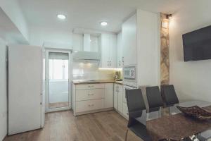 a kitchen with white cabinets and a glass table with chairs at Alojamiento Suit Royal in Úbeda