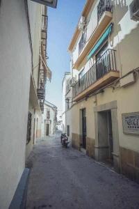 een leeg steegje tussen twee gebouwen met een auto erop geparkeerd bij Alojamiento Suit Royal in Úbeda