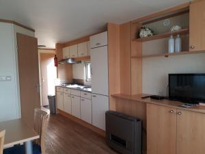 a small kitchen with white cabinets and a television at Chalet de Boshoorn in Serooskerke