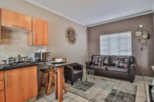 een keuken en een woonkamer met een bank en een tafel bij Rudman Townhouses - OR Tambo Airport in Boksburg