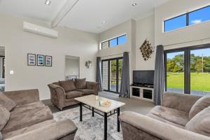 a living room with two couches and a tv at Tutukaka Treat - Wellingtons Bay Holiday Home in Tutukaka