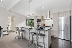 a kitchen with a bar with stools and a refrigerator at Tutukaka Treat - Wellingtons Bay Holiday Home in Tutukaka +11 photos