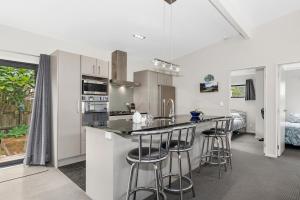 a kitchen with white cabinets and bar stools at Tutukaka Treat - Wellingtons Bay Holiday Home in Tutukaka