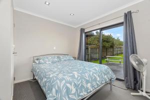 a bedroom with a bed and a large window at Tutukaka Treat - Wellingtons Bay Holiday Home in Tutukaka