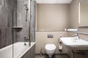 a bathroom with a toilet and a sink and a bath tub at Ibis Poznan Centrum in Poznań