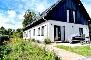 a small white house with a black roof at Spreewald - Ferienhaus - Wilhelmine in Burg