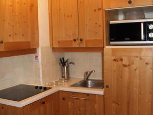 a kitchen with wooden cabinets and a sink and a microwave at Appartement 6 pers avec piscine, parking et WiFi, à deux pas des pistes. - FR-1-508-234 in Lanslebourg-Mont-Cenis +4 photos