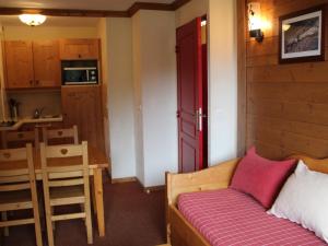 a bedroom with a bed with a red door and a kitchen at Appartement Lanslebourg-Mont-Cenis, 3 pièces, 6 personnes - FR-1-508-234 in Lanslebourg-Mont-Cenis