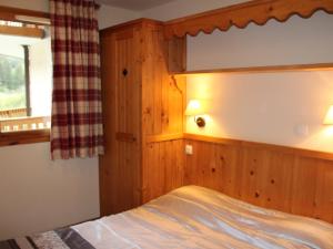 a bedroom with a bed with a wooden wall at Appartement 6 pers avec piscine, parking et WiFi, à deux pas des pistes. - FR-1-508-234 in Lanslebourg-Mont-Cenis