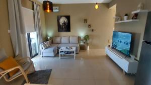 ein Wohnzimmer mit einem weißen Sofa und einem TV in der Unterkunft Paramount Gardens Resorts C202 in Larnaka