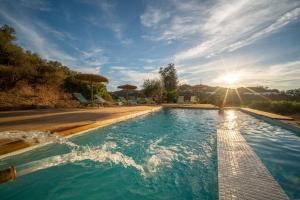 una piscina con el sol en el cielo en Finca Contrabando completa 20 pax, en Huelva