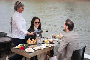 Una donna che versa vino a un tavolo su una barca di Hotel Restaurant Brasserie Feestzaal Ahoi, Kortrijk a Courtrai