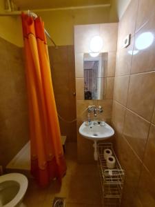 a bathroom with an orange shower curtain and a sink at Jocó Panzió in Nyíregyháza