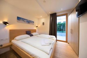 a bedroom with a large white bed and a window at FamilienWohnung Wildspitze am Sonnenhang in Neukirchen am Großvenediger