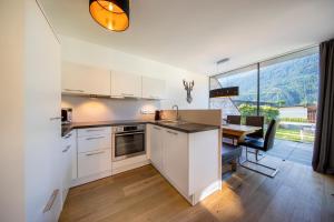 a kitchen with white cabinets and a dining table at FamilienWohnung Wildspitze am Sonnenhang in Neukirchen am Großvenediger