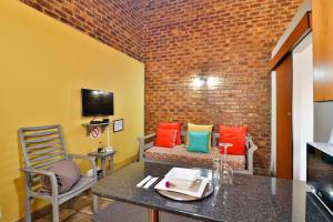 Rudman Townhouses Self-catering Accommodation في بوكسبرغ: غرفة مع طاولة وكراسي وجدار من الطوب