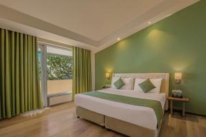 a bedroom with a large bed with green walls and a window at Sterling Mussoorie in Mussoorie