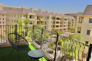 uma varanda de um apartamento com uma mesa e uma cadeira em Unified Vacation Homes-Spacious Studio in lush green Motor City no Dubai