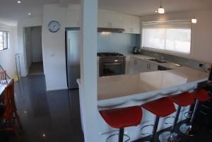 una cucina con bancone e alcuni sgabelli rossi di Award Winning Beach Front Retreat a Frankston