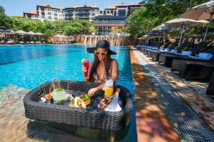 a woman with a tray of food next to a pool at The Capital Zimbali in Ballito