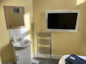 ein Bad mit einem Waschbecken und einem TV an der Wand in der Unterkunft The Beach Side in Redcar