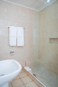 a bathroom with a tub and a sink and a shower at Hotel Hibiscus Blvd Triomphal in Libreville