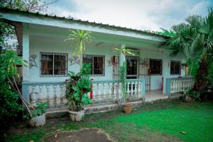een wit huis met een veranda en een aantal planten bij Hotel Hibiscus Blvd Triomphal in Libreville